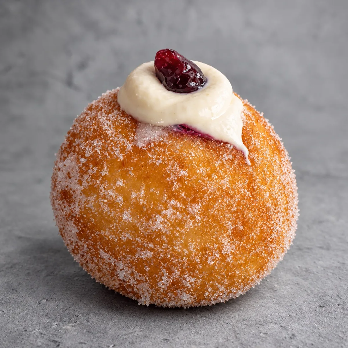 Blueberry bomboloni rolled in sugar with vanilla cream and a blueberry on top